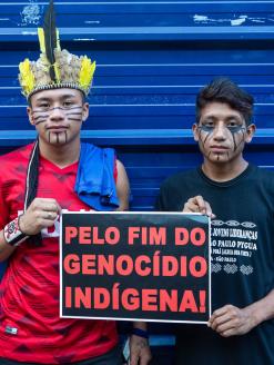 Two young indigenous men protesting holding banner "Stop the indigenous genocide", in march for the rights of the indigenous people.  São Paulo, Brazil. 1 January 2019. Editorial Credit: PARALAXIS / Shutterstock.com