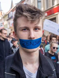Teenaged man with taped mouth protesting censorship at demonstration against a new copyright law by European Union, "Artikel 13." Erfurt, Germany. 23 March 2019. Editorial credit:  Timo Nausch / Shutterstock.com