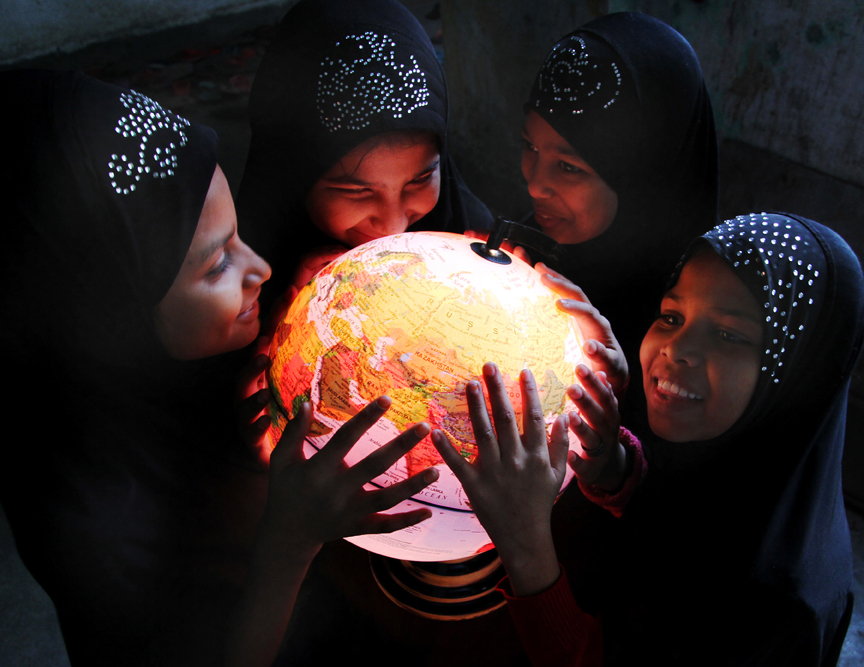 women and girls hold lit globe map of world