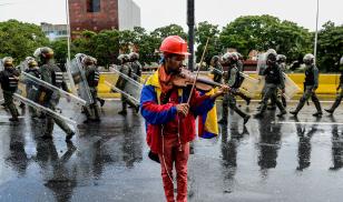 An opposition demonstrator plays the violin during a protest against President Nicolas Maduro in Caracas. Credit: FEDERICO PARRA/AFP/Getty Images.